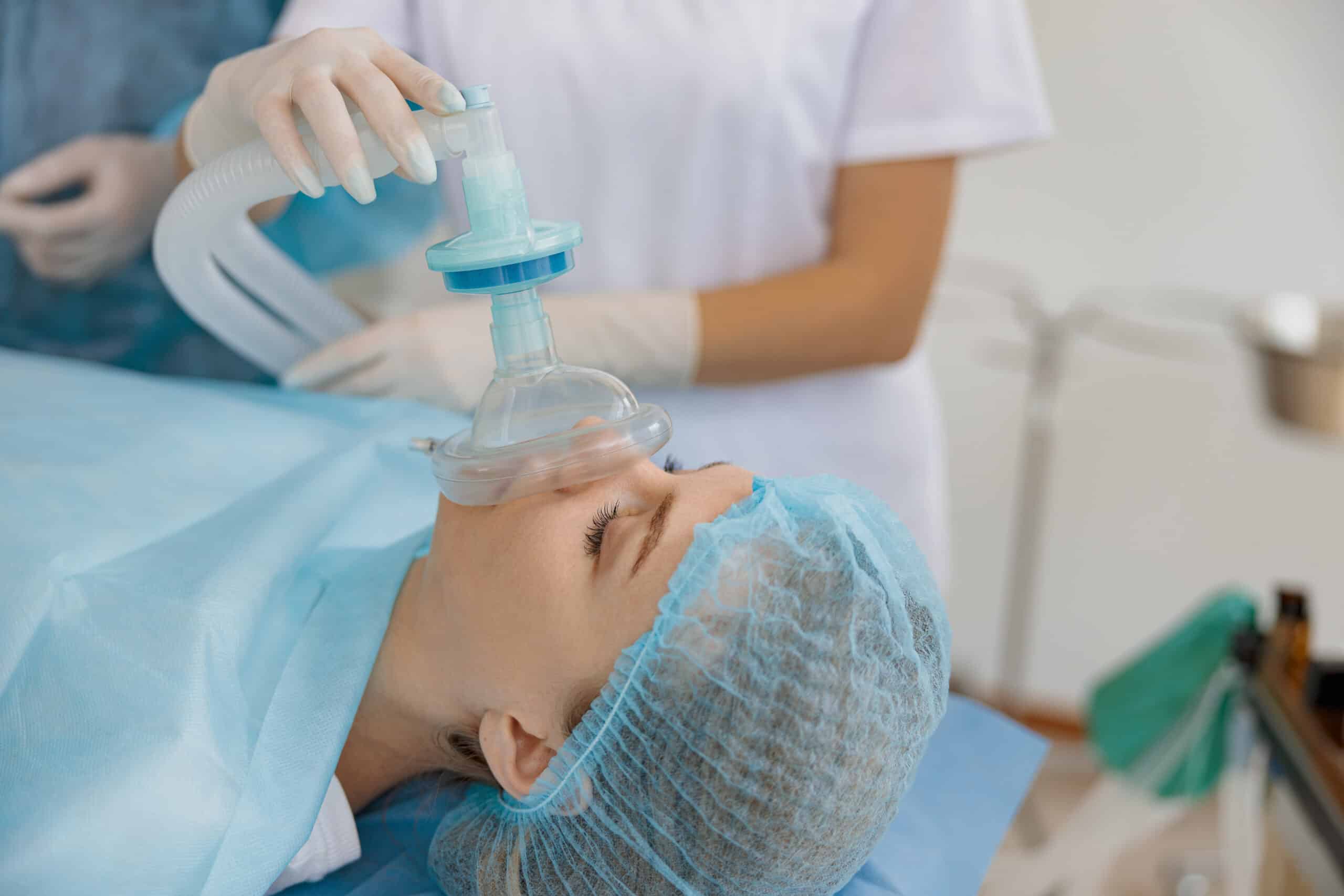 an anesthesiologist holding an oxygen a mask on a patent's  face